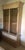 Classical clear glass armoire. Wood and tan leather dim lighting display cabinet with shelves and storage. Silver and...