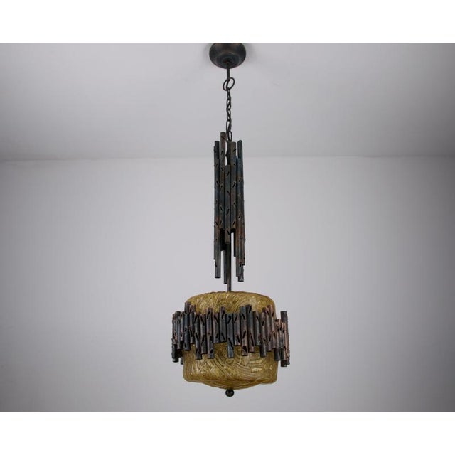 Brutalist pendant lamp from Germany, 1970s, combining a heavy textured amber glass shade with a striking construction of...
