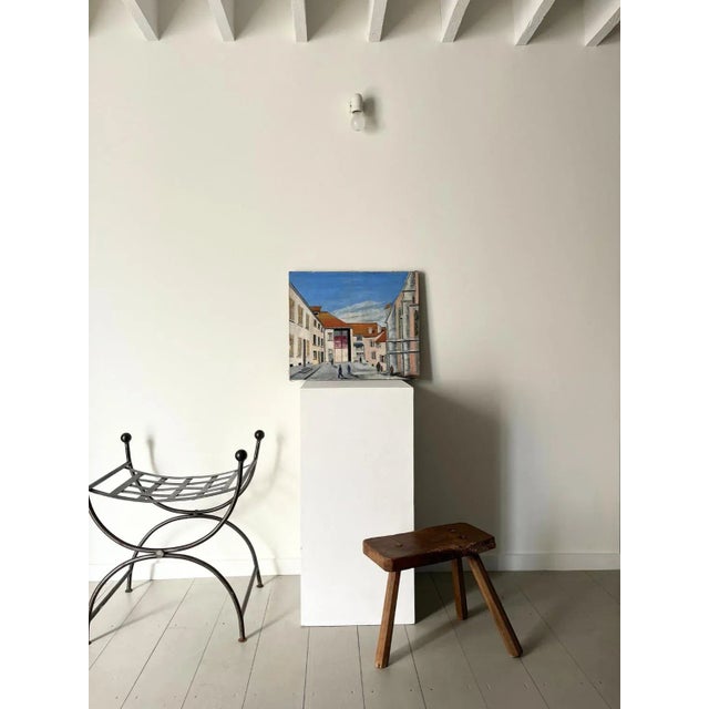 A mid century french oil painting depicting a european townscape. This vintage artwork has a naive style, featuring block...