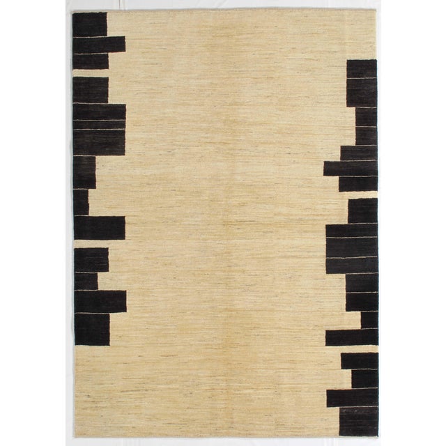 Hand-knotted Persian Lori Gabbeh rug featuring a soft ivory field with bold, asymmetrical black geometric forms along the...