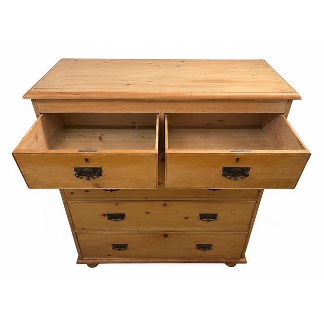 A 1890s five-drawer pine dresser, bronze pulls and bun feet.