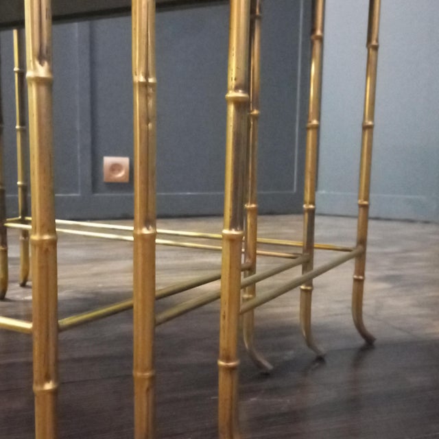 Set of three faux bamboo nesting tables with tinted mirror glass by the French firm Maison Baguès. Gold-tone finish with a...