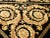 Central medallion in gold tone on a black background filled with floral motifs. Hand knotted and hand carved. Wool pile on...