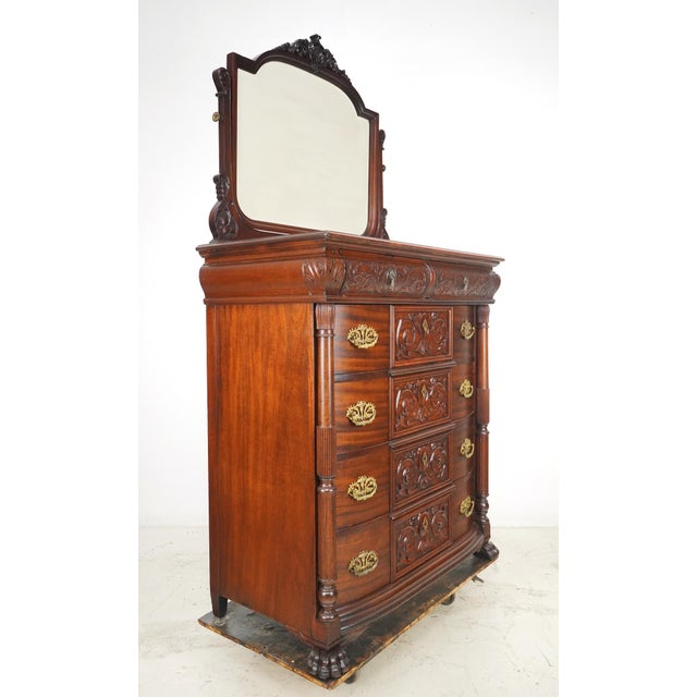 Victorian style bedroom dresser with a beveled mirror and deeply carved reliefs. It features the original brass hardware...