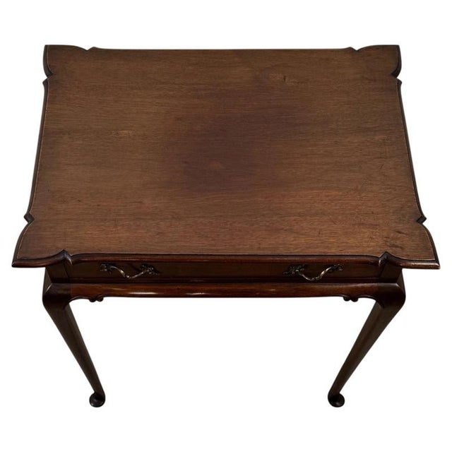 An elegant early 20th-century English side table, finely crafted from mahogany and distinguished by its beautifully shaped...