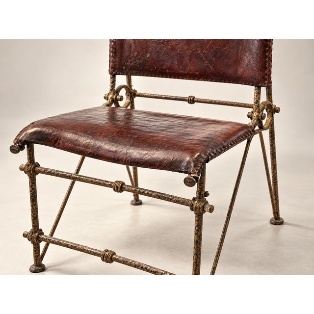 A striking vintage iron and leather chair with true character and presence. The frame is crafted from hand-forged iron...