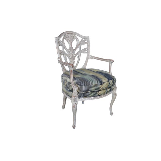 An antique carved wooden arm chair with a Sheraton style seat back in a traditional shield shape. Solid wood frames are...