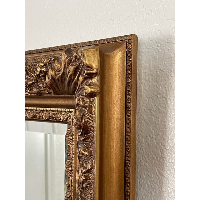 This Mid-Century Bella French style ornate giltwood beveled wall mirror features a rectangular design with a heavily...