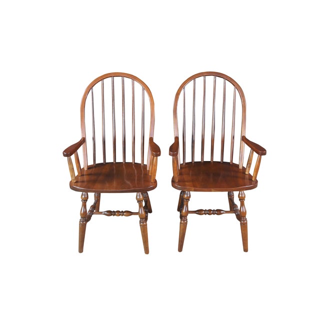 Vintage pair of two Amish made arm chairs. Made of oak featuring a high spindle bow back design with turned legs connected...
