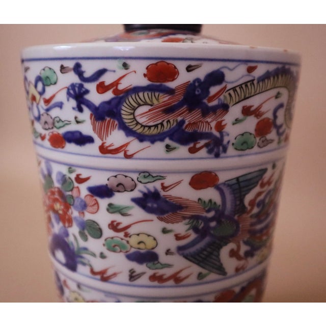 Antique hand-painted jar with dragons, phoenixes and florals in hues of red, blue, yellow and green over white background....