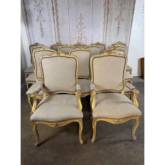 An exceptional set of fourteen French Louis XV style dining chairs, including twelve side chairs and two armchairs,...