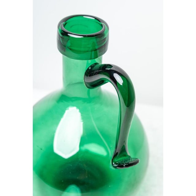 Green glass pitcher, Made in Italy, 1950s. Peculiar thick green glass pitcher from the 1950s, with a handle that features...
