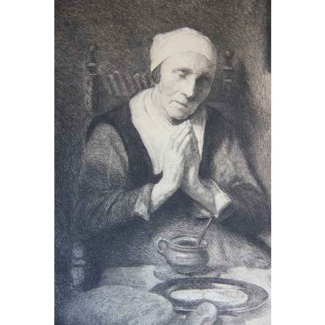 Portrait of a woman praying at a table with food. In the corner a cat reaching up to see over the table. The etching is...