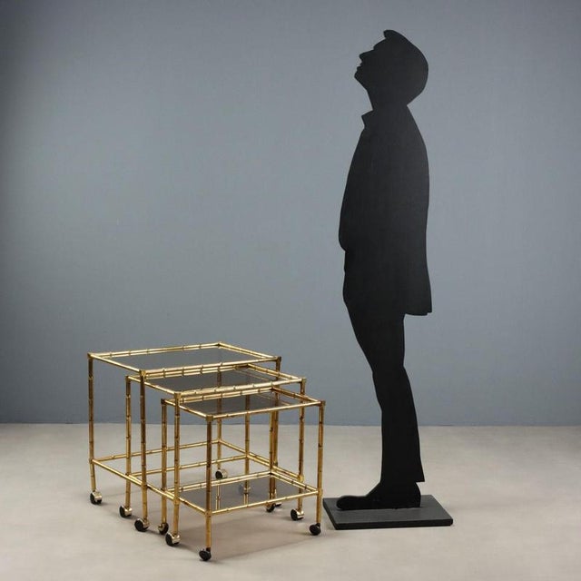 This trio of 1980s brass and smoked glass coffee tables is an example of the elegant and functional design of the era. The...