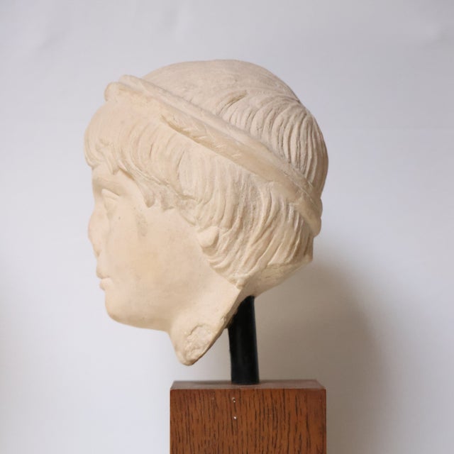 This 20th century French marble bust of a child is delicately carved and elegantly presented on a solid oak pedestal. Its...