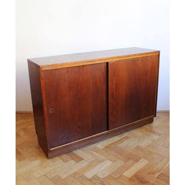 A beautifully restrained oak sideboard produced by UP Závody in Czechoslovakia in 1966. The cabinet is defined by its...