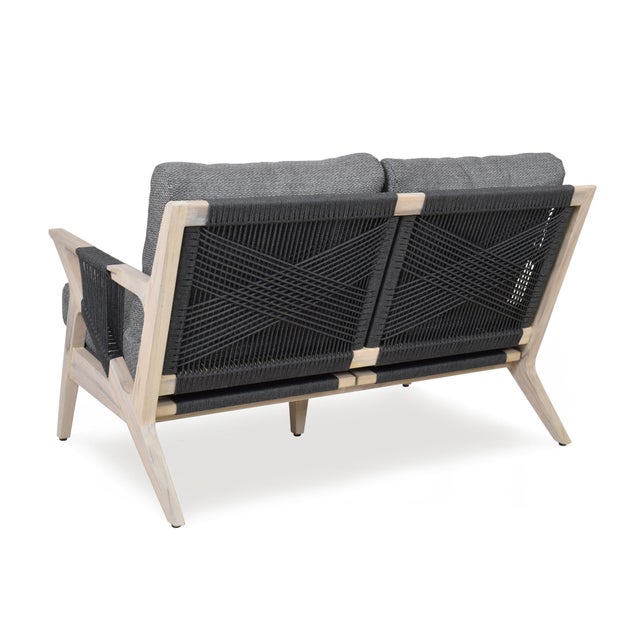 A relaxed loveseat adapted from a Hans Wegner 1960's original, with a rope woven and teak frame supporting ample cushions...