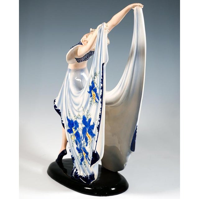 Gracefully posing dancer in blue costume: dark blue dotted bustier with light blue ruffled sleeves and short skirt in...