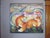 In "Fox Lake," two vibrant foxes engage in a quiet moment of reflection, their rich orange fur contrasting against a...