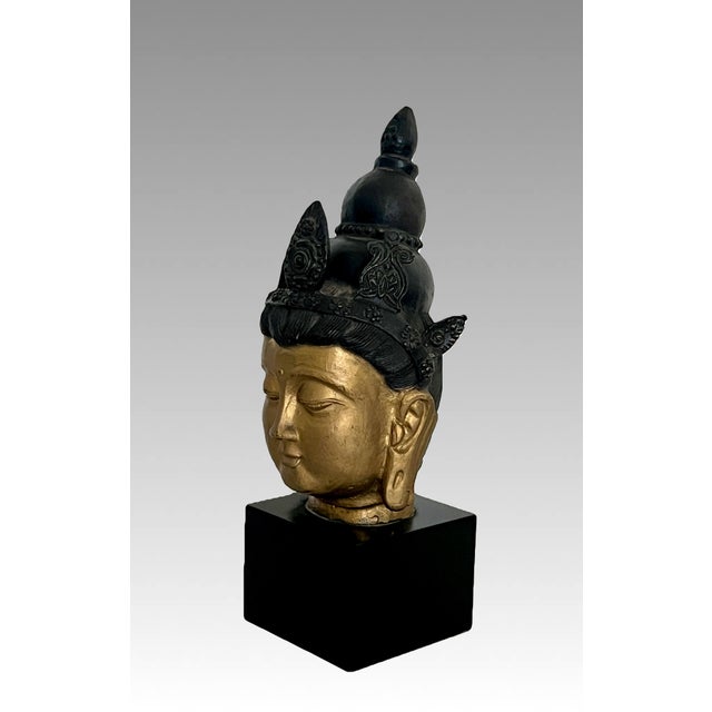 An eye catching golden image of Buddha mounted on a high quality black square pedestal. Identified as a depiction of...