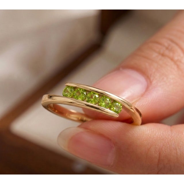 Discover effortless modern elegance with this striking peridot bypass ring. This contemporary piece features a sleek,...