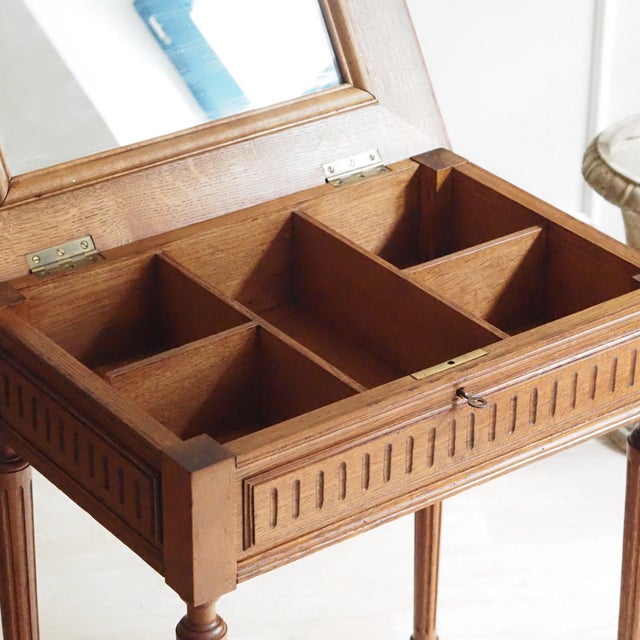 A Louis XVI-style side table, crafted in oak around 1900, with a hinged top, an integrated mirror, and a divided...