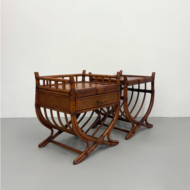 A beautifully crafted pair of vintage British Colonial nightstands featuring bamboo and rattan construction with woven...