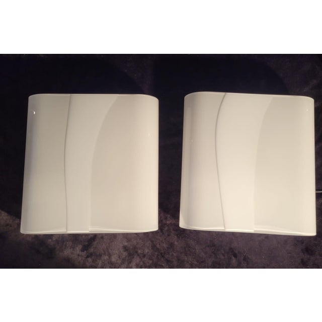 An elegant pair of vintage Italian wall lamps from the 1970s, crafted from Murano glass with a lacquered metal frame. The...