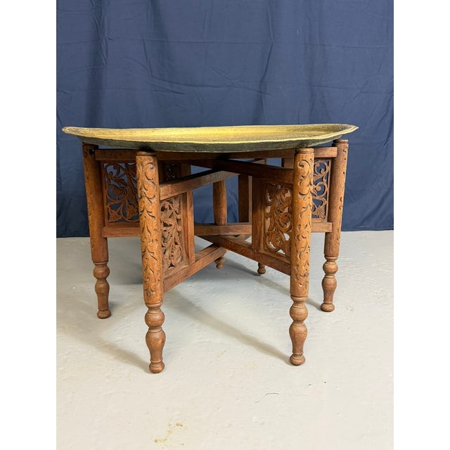 Antique Anglo-Indian Benares Brass Tray Table with Hand-Carved Folding Wooden Base, 1910, in Good conditions. Designed...