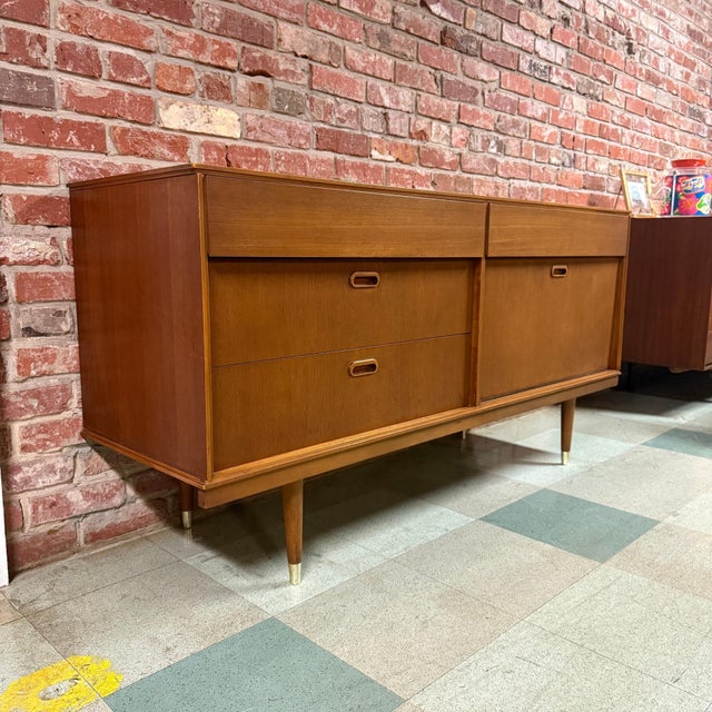 Vintage mid-century modern teak sideboard or credenza manufactured by Avalon of Yatton, UK. Features two upper drawers,...