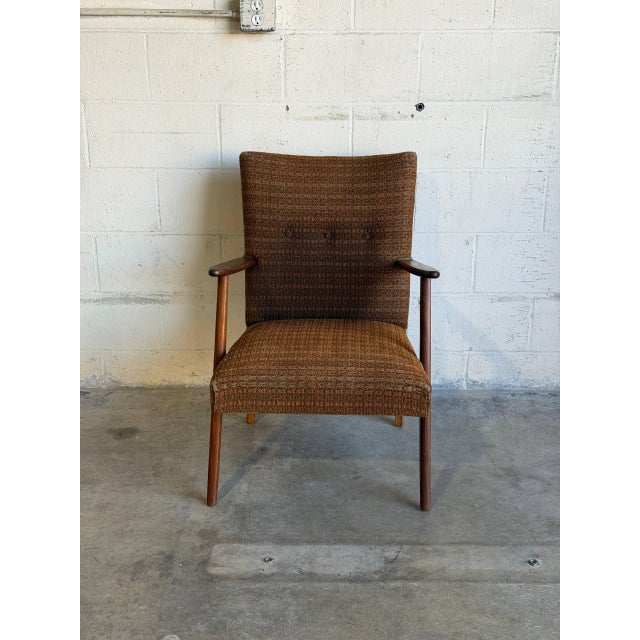 This vintage lounge armchair features an angled frame with sculptured armrests and a tufted backrest. The design...