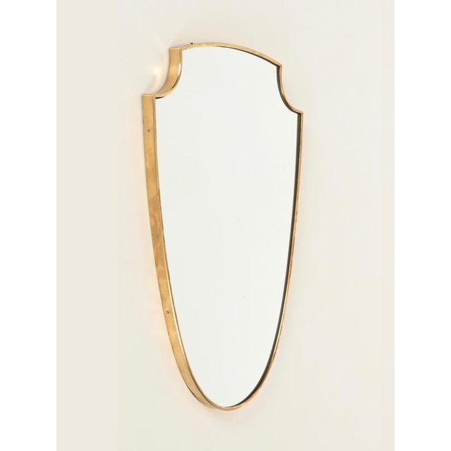 Stunning shield-shaped mirror with a solid brass frame. This incredibly elegant piece was produced in Italy during the...