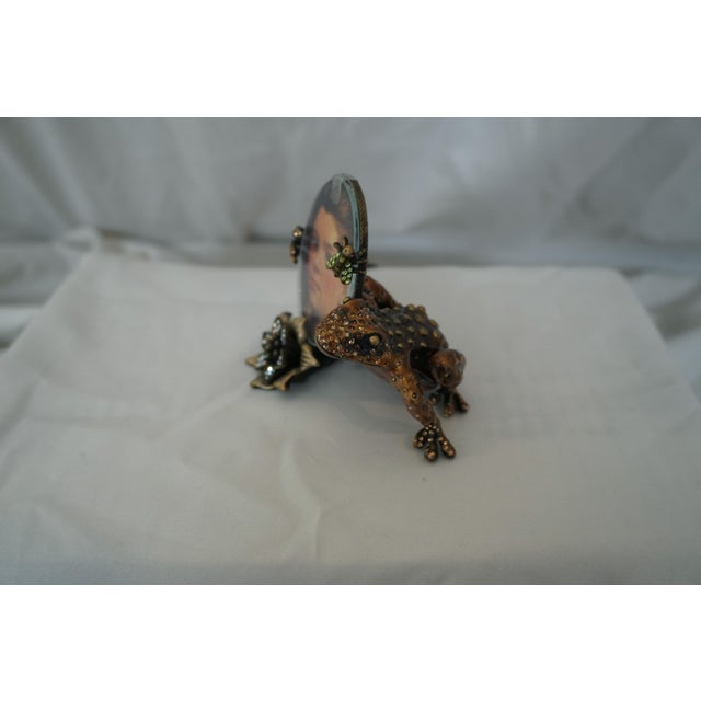 Jay Strongwater Enamel & Jewel Frog Frame Showcases a frog, hold on to an oval shaped frame. A fly / bee with green...