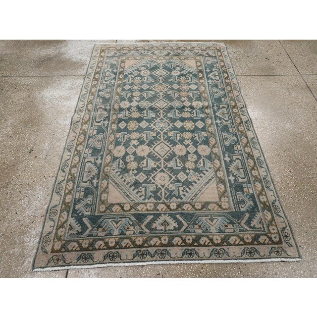 This mid-20th-century Persian Malayer throw rug presents a finely organized allover composition across a deep muted blue-...
