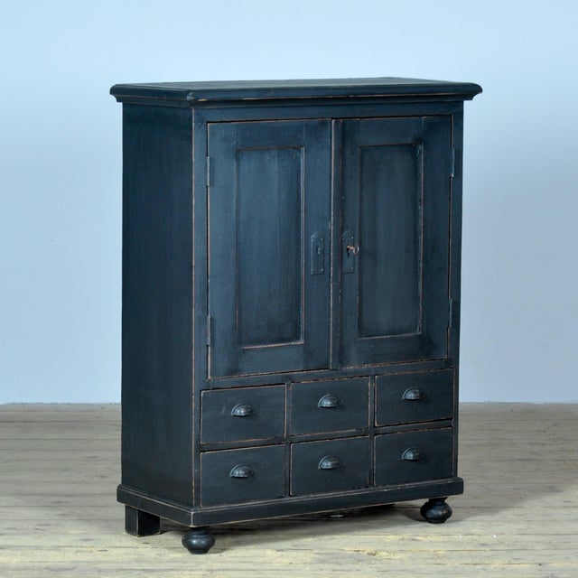 An atmospheric pine cabinet with a characterful, lived-in look. It features two doors with authentic escutcheons and a...