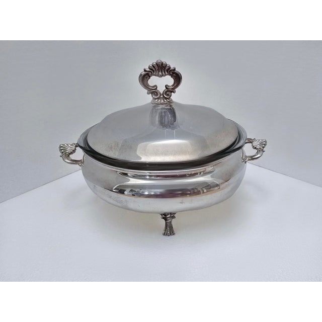 A set of two FB Rogers silver plate serving dishes with Pyrex inserts. One is three-legged with burner on bottom. Second...