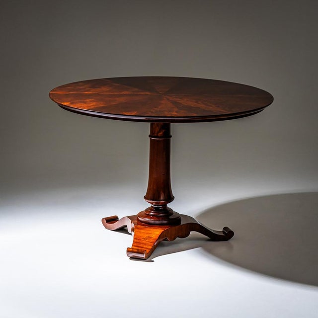 Center table with a circular top featuring a radial veneer pattern, raised on a tapered column with accent rings and a...