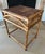 Circa 1970s rattan / bamboo side table with ornate trim and woven top. Sturdy, measures 26" tall x 17" x 21.5". Minor age...