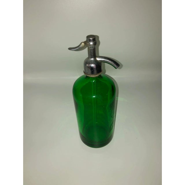 A green glass seltzer bottle with chrome dispenser top. Circa 1900 purchased tin France.