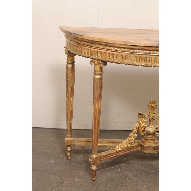 An elegant French Neoclassical carved giltwood demi-lune console table, with exceptional marble top, from the early 19th...