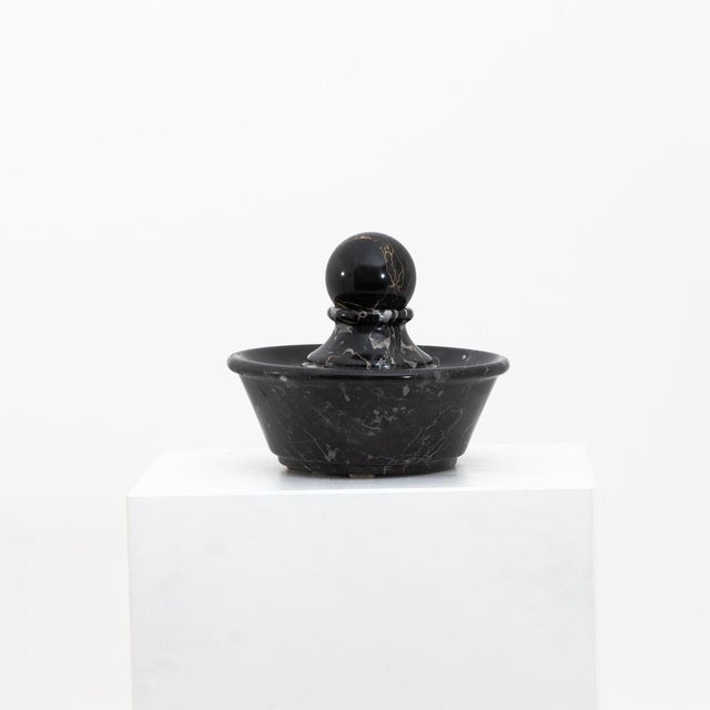 Small round table in black marble fountain with spherical cap.