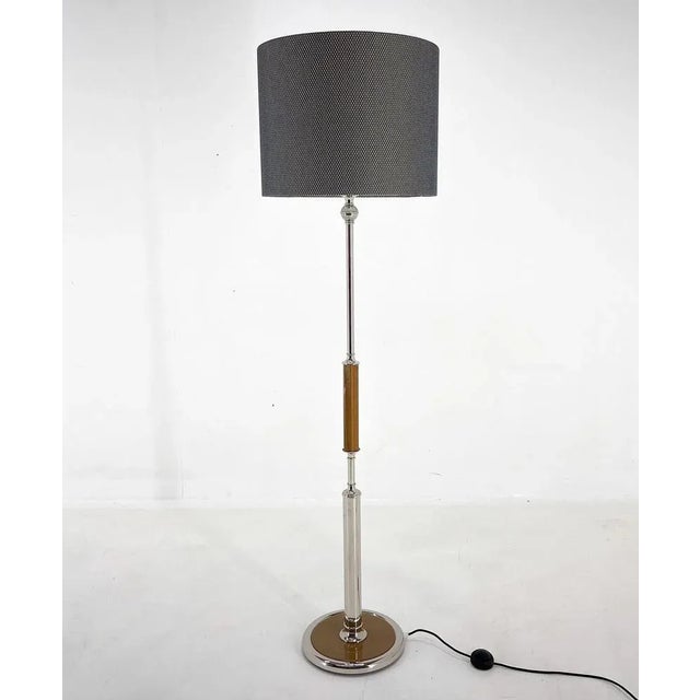 Mid-century floor lamp from Former Czechoslovakia. Made of chrome and wood with step-on switch. The lamp was restored, has...