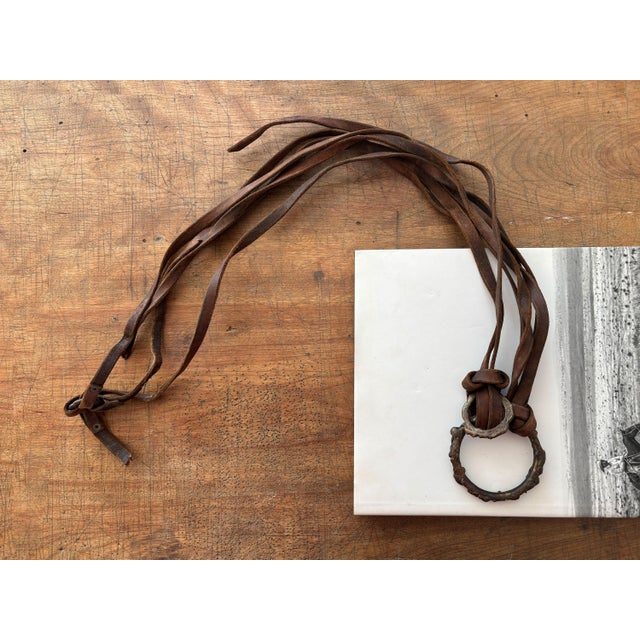Here is a vintage leather harness strap wall-hanging decor piece, featuring abstract welded brass rings with assorted...