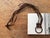 Here is a vintage leather harness strap wall-hanging decor piece, featuring abstract welded brass rings with assorted...