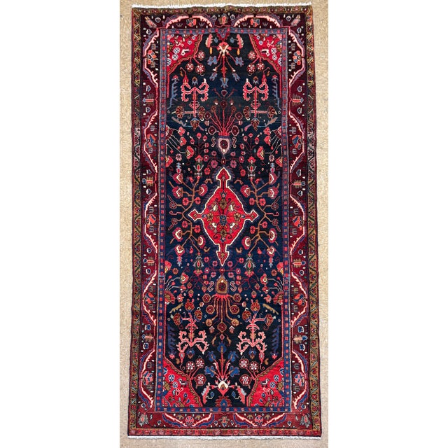Hand-knotted runner from the Hamadan region of western Iran, featuring a large central medallion set within a deep navy...