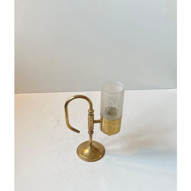 A nautical/maritime chamberstick executed in solid brass and featuring a tubular shade in frosted glass with a ship fregat...