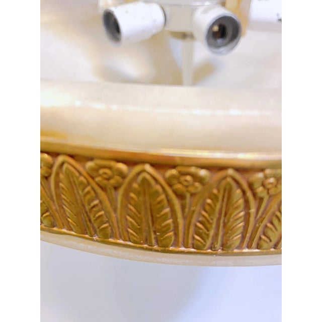 Beautiful pendant lighting fixture with intricate detailing in a bronze finish rim and a cream colored alabaster bowl. The...