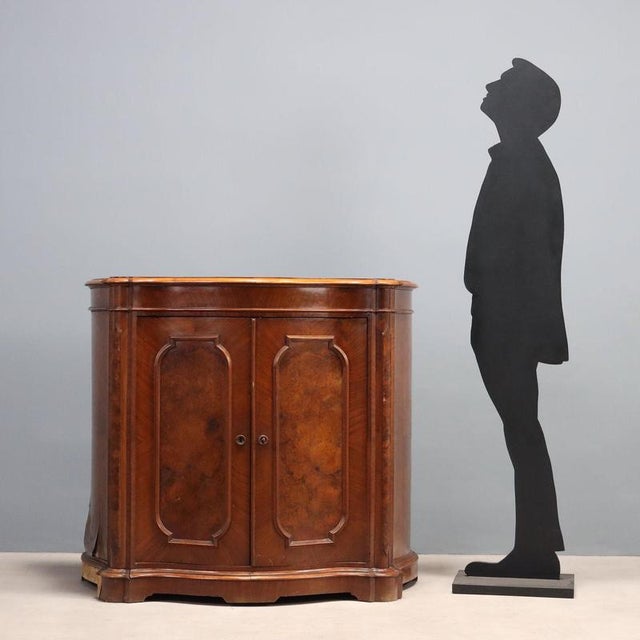 Umbertina sideboard in walnut and walnut burl. Curved front and sides, pair of paneled doors, and bracket feet. Some...