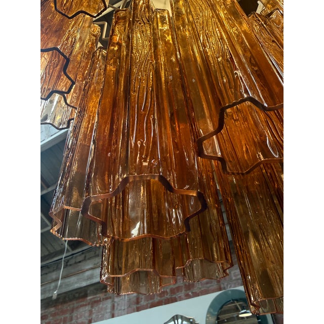Striking Italian chandelier composed of cascading tiers of textured amber Murano glass “tronchi” elements. The sculptural...