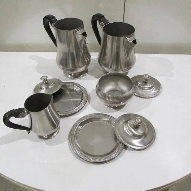 This art deco style coffee and tea set is made of stainless steel with bakelite handles. It is marked with the létang &...
